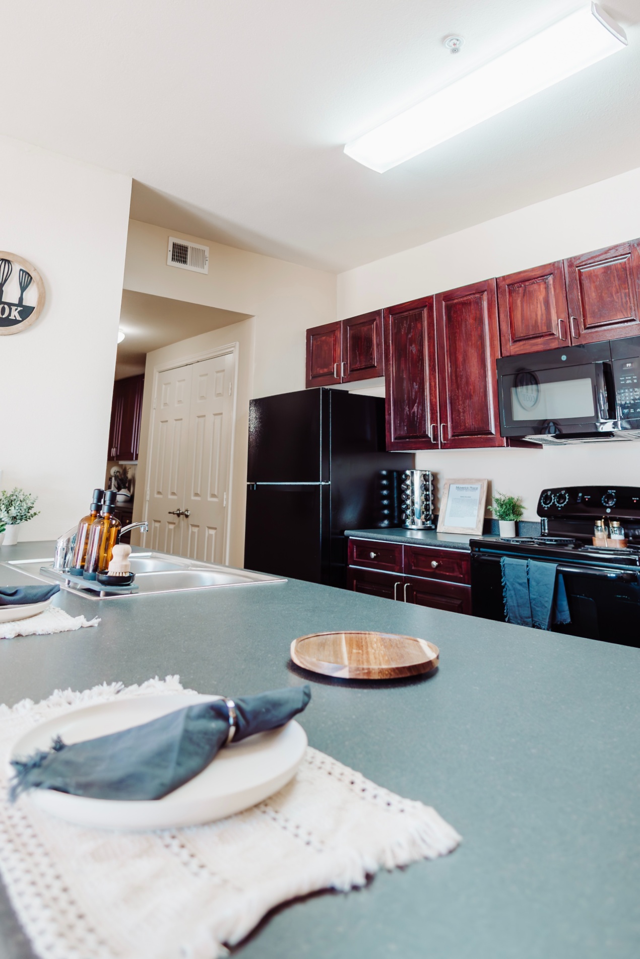 Kitchen with double stainless steel sink and black appliances at Maverick Place