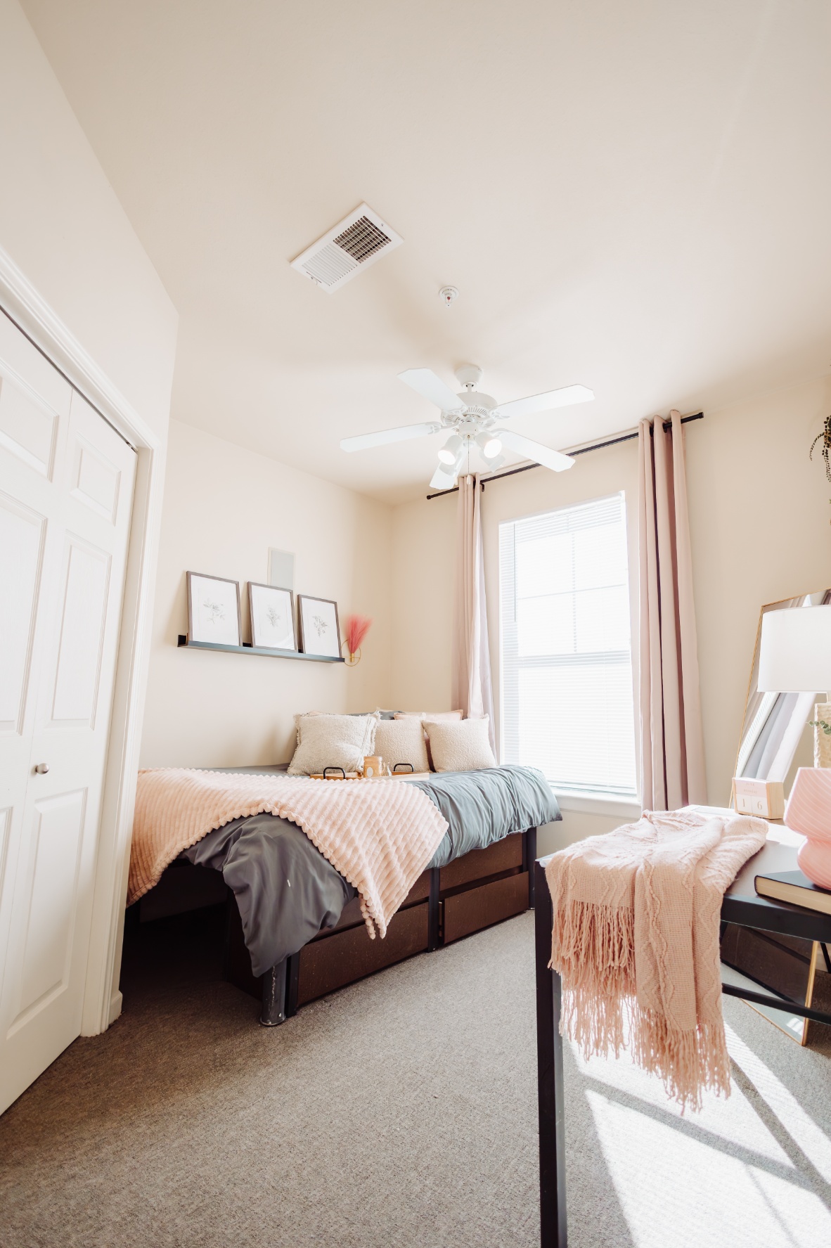 Model bedroom with ceiling fan and large window at Maverick Place